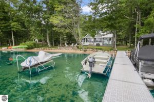 Waterfront home on Green Lake in Interlochen offers private frontage with a sandy beach area for kids and a private dock for mooring the boats and water vehicles. Listed by Stapleton Realty.