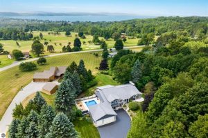 Golf, swim, anyone? photo is an aerial shot of the house, garage and in-ground pool surrounded by trees with an opening to a view of Crystal Lake in Benzie County.